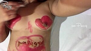 En tonårstjej skissar på sin nakna asiatiska kropp med läppstift i en hemmagjord video